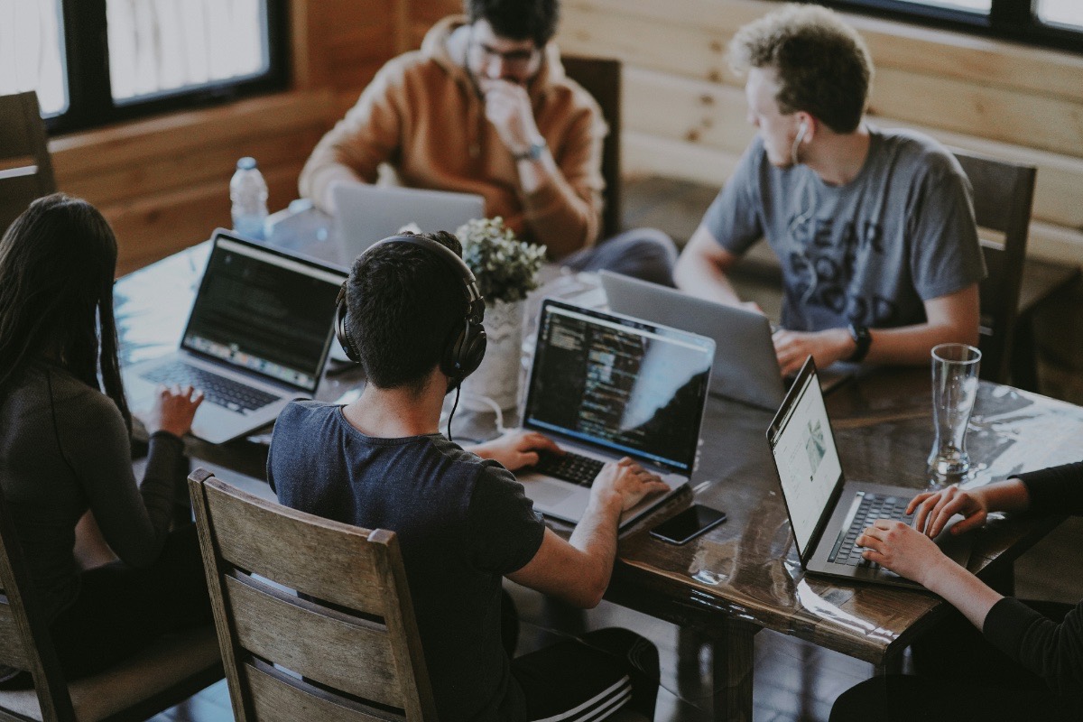 Software development team working together on laptops around a shared table
